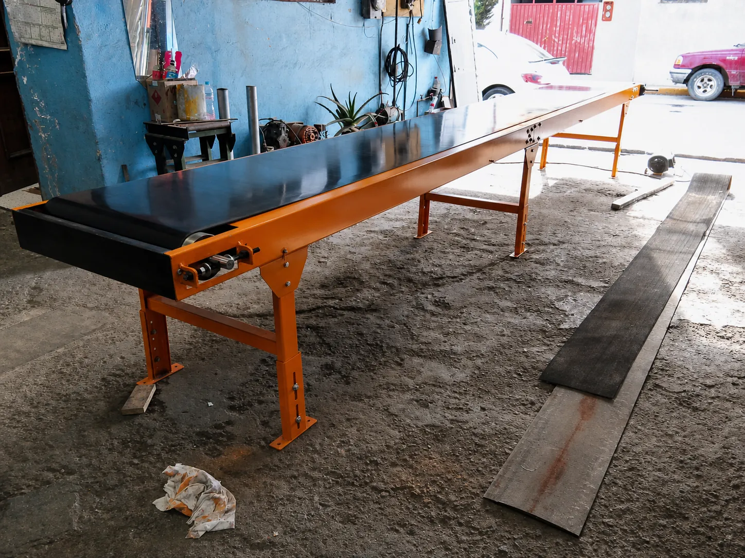 Transportador de banda negro con estructura naranja fabricado en el taller AREDI